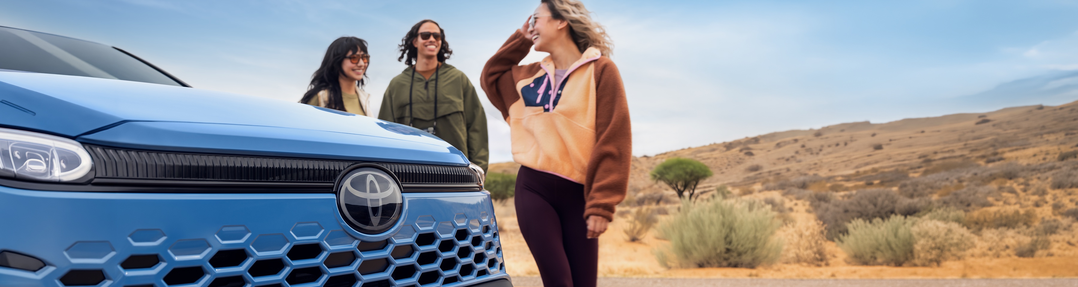Friends laughing next to a Toyota Corolla Cross Hybrid